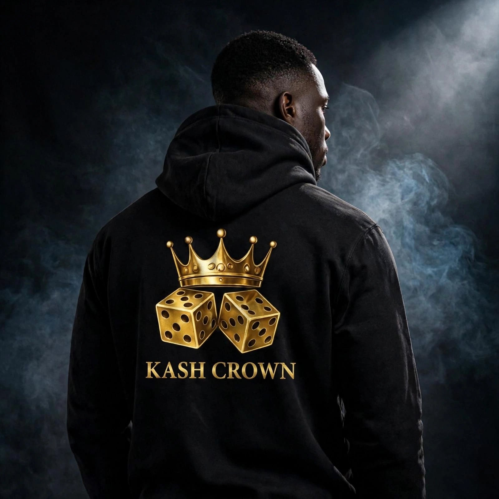 Model wearing the black KASH CROWN Crown & Dice Hoodie, back view against a dark smoky studio background, gold crown and dice graphic