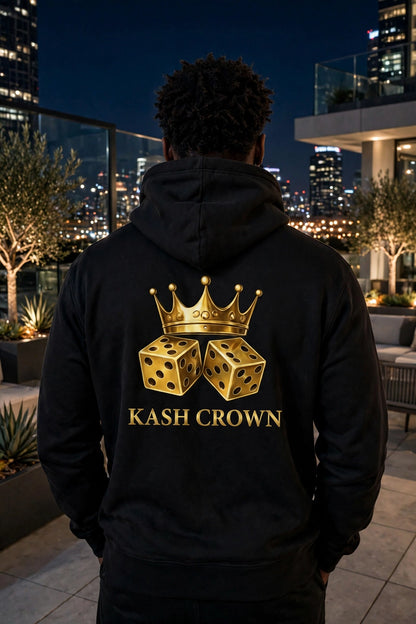 Back view of the black KASH CROWN Crown & Dice Hoodie on a rooftop at night with a city skyline behind, gold crown and dice graphic